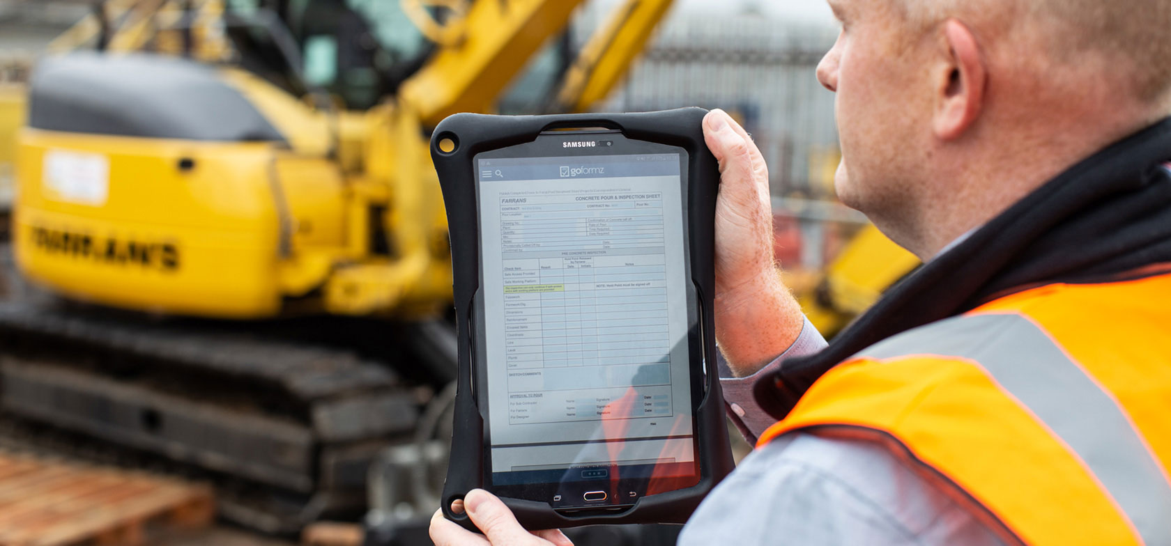Farrans Construction engineer holding tablet displaying the GoFormz app, while wearing a safety vest