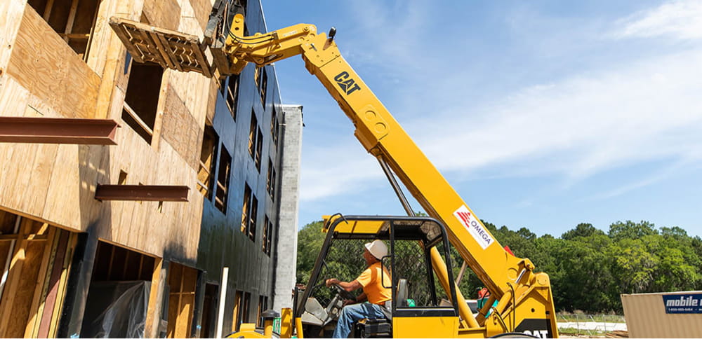 Photo of an Omega Construction employee operating a heavy duty lift on a job site